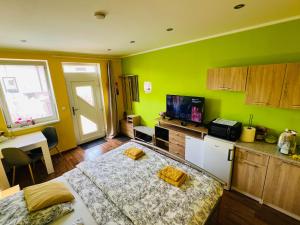 a room with a bed and a kitchen with green walls at Apartmán Slivková in Trenčín
