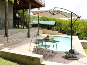 a table with an umbrella next to a swimming pool at Meulensrus in Hoedspruit