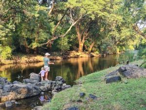 a man and a child standing on rocks near a river at Meulensrus in Hoedspruit