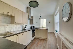 a kitchen with white cabinets and a clock on the wall at 3 Bed in Cromer oc-1727 in Cromer +14 photos