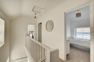 a white hallway with a staircase and a mirror at 3 Bed in Cromer oc-1727 in Cromer