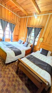 two beds in a room with wooden walls at Accomoon Valleyside homes in Mechuka +10 photos