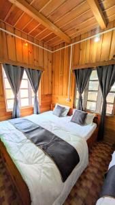 a large bed in a room with wooden walls at Accomoon Valleyside homes in Mechuka