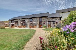 a stone building with tables and chairs in a garden at 1 Bed in Tiverton oc-gear in Bampton