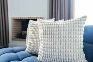 two white pillows sitting on a blue couch with a fireplace at Résidence Luxe avec Plage Privée in Bouznika