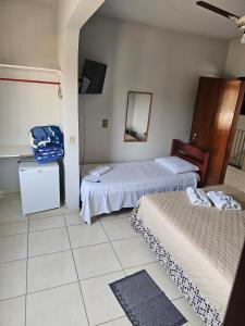 a room with two beds and a mirror and a tv at Hotel pousada vista alegre in Itapeva