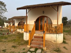 a small house with a staircase leading to a porch at The Tarai Pilibhit in Kālīnagar