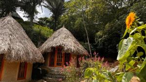 ein kleines Haus mit zwei Strohdächern und Blumen in der Unterkunft Tawaca SANCTUARY in Calabazo