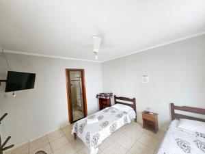 a bedroom with two beds and a flat screen tv at Hotel Itapeva vista alegre in Itapeva