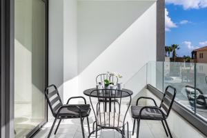 a glass table and chairs on a balcony with a view at Hinoki 2-Bedroom Apartment in Larnaca