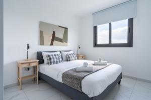 a white bedroom with a large bed and two windows at Hinoki 2-Bedroom Apartment in Larnaca