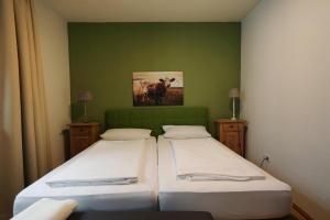 two beds in a room with a green wall at Gasthaus Grüner Baum in Prichsenstadt