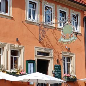 an orange building with an umbrella in front of it at Gasthaus Grüner Baum in Prichsenstadt