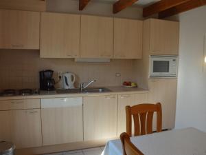 a kitchen with wooden cabinets and a sink and a microwave at Gezellig vissershuis in De Haan