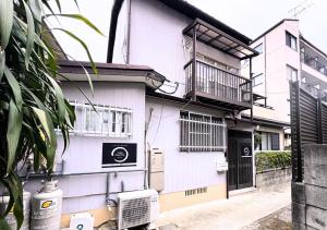a white building with a door and a balcony at Nishijin Stay One in Fukuoka