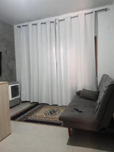 a living room with white curtains and a couch at Jardim Primavera in Palmas