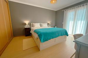 a bedroom with a bed with a blue blanket on it at Marta Apartment - Balcony, Patio, Pool in Ferrel +19 photos