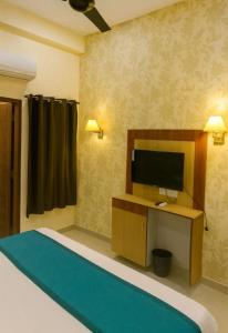 a bedroom with a bed and a television on a desk at Hotel Royale Elite RK Residency in Vrindāvan