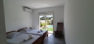 two beds in a room with a window at CASA VIGNA - villa T4 piscine privée in Sainte-Lucie de Porto-Vecchio