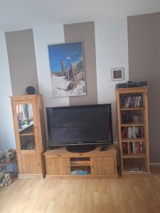Ein Flachbildfernseher, der auf einem Holzständer in einem Wohnzimmer steht. in der Unterkunft Piacere Emden in Emden