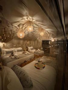 a bedroom with three beds and two chandeliers at Peaceful Luxury Camp in Merzouga