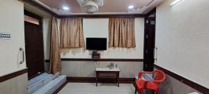 a room with a television and a red chair at Hotel Shri Shanti Niwas in Bikaner +1 photo