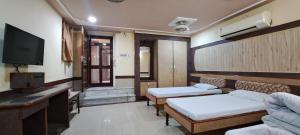 a room with two beds and a flat screen tv at Hotel Shri Shanti Niwas in Bikaner