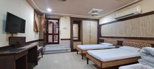 a room with two beds and a flat screen tv at Hotel Shri Shanti Niwas in Bikaner