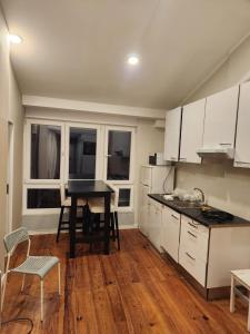 a kitchen with white cabinets and a table and chairs at Daora Lisbon Beds in Lisbon