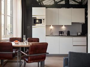 a kitchen with white cabinets and a table with chairs at YAYS Amsterdam Maritime by Numa in Amsterdam
