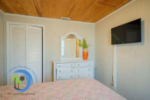 a bedroom with a bed and a dresser and a tv at Cg Beach Bungalow #1 in Myrtle Beach