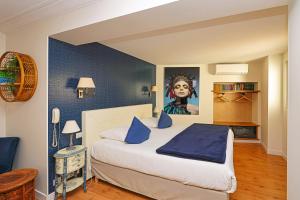 a bedroom with a bed with a painting on the wall at Charming Hôtel - Les Pasteliers in Albi