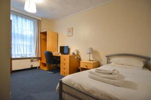 a bedroom with a bed and a desk with a computer at Luther King House in Manchester