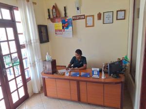 a woman sitting at a counter in a restaurant at Rainbow Executive Lodge in Boma la Ngombe