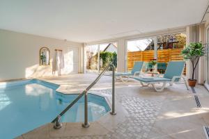 a swimming pool in a house with blue chairs at Romantic 4-star suite with private heated pool in Gimbrett