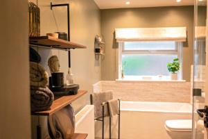 a bathroom with a tub and a toilet and a window at Nadder Lodge - Salisbury in Old Sarum +28 photos