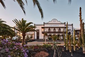 a building with palm trees in front of it at Seaside Los Jameos in Puerto del Carmen