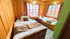 a room with two beds in a wooden cabin at Accomoon Valleyside homes in Mechuka