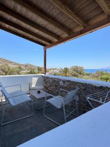 a patio with chairs and a table and a stone wall at Iosub Houses & Studios - Cosy Seaside House in Koumbara in Tzamaria