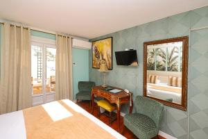 a bedroom with a bed and a desk and a mirror at Charming Hôtel - Les Pasteliers in Albi