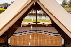 a bed in a tent with a boat in the water at Bell Tent aan de haven in Heerewaarden