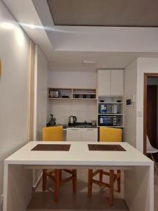 a kitchen with a white table and yellow chairs at Toscana Apart in San Miguel de Tucumán