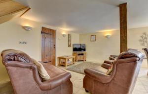 a living room with two leather chairs and a television at 3 Bed in Tiverton oc-thresh in Bampton