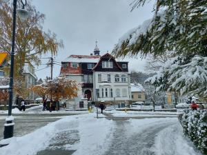 a snow covered street in front of a house at Roland Apartamenty in Świeradów-Zdrój