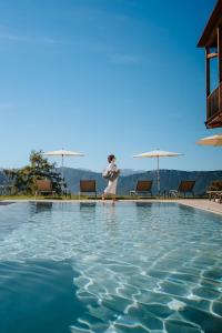a woman is standing next to a swimming pool at Hotel am Hang in Soprabolzano