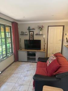 a living room with a couch and a flat screen tv at Rose Thatch Cottage in Howick
