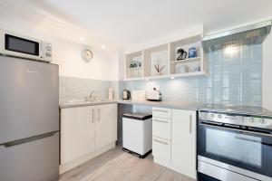 a white kitchen with white cabinets and appliances at 1 Bed in Parracombe oc-smitho in Trentishoe +9 photos