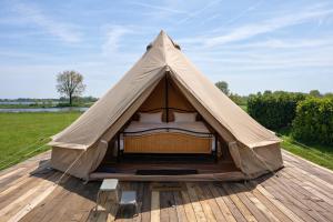 a canvas tent on a wooden deck in a field at Bell Tent aan de haven in Heerewaarden
