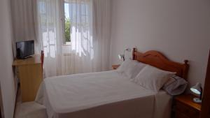 a bedroom with a white bed and a window at Casa Bruna 1º A Apartamento a 800 m de la playa in Lariño