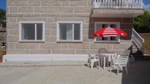 a table with a red and white umbrella next to a building at Casa Bruna 1º A Apartamento a 800 m de la playa in Lariño